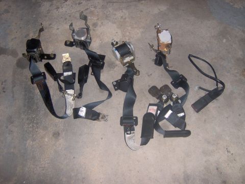 1994 Ford Probe - Multiple seat belt assemblies are laid out on a concrete surface.
