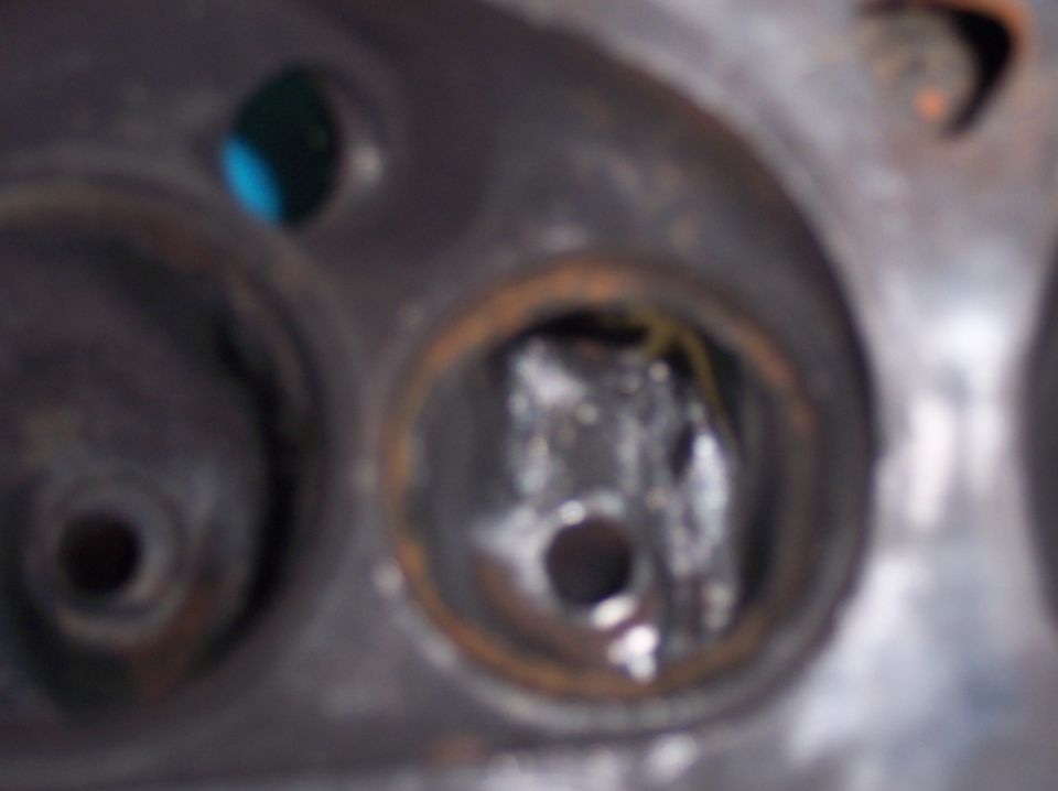 Close-up of engine cylinder head with two openings, one showing damage