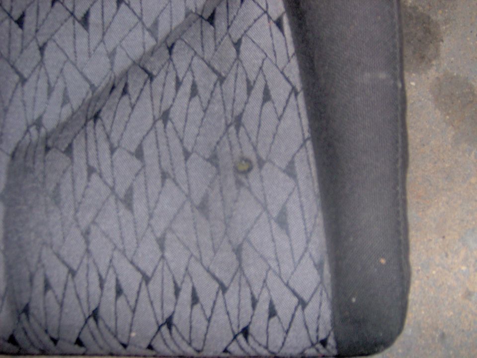 Close-up of gray car seat fabric with a diamond pattern and a small stain