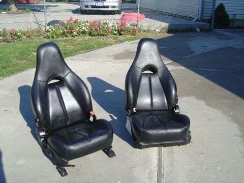 1995 Ford Probe - Pair of black leather bucket seats, likely for a sports car, displayed outdoors on a concrete surface.