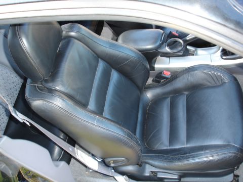 1995 Ford Probe - Interior view of a worn black leather car seat with a seatbelt.