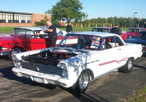 1979 Ford F-150 - A white classic coupe is displayed with its hood open, parked at an outdoor event with other vehicles.