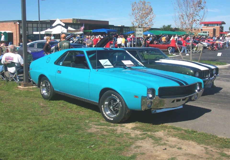 Blue 1970 AMC Javelin with black racing stripes parked at an outdoor car show