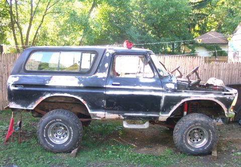 1979 Ford F-150 - This 1979 Ford Bronco, seen from the side, shows significant wear and tear with peeling paint and modified off-road tires.