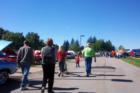 1979 Ford F-150 - Attendees stroll through an outdoor car show on a sunny day, with various vehicles and tents lining the street.