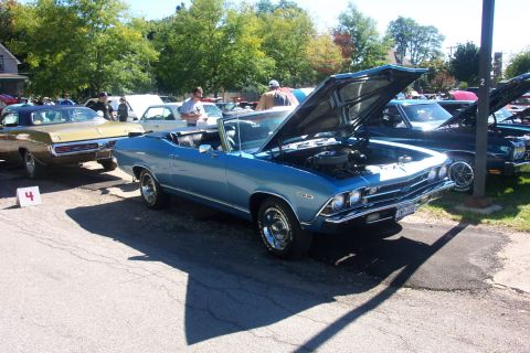 1979 Ford F-150 - A blue 1969 Chevrolet Chevelle convertible is displayed with its hood open at an outdoor car show.