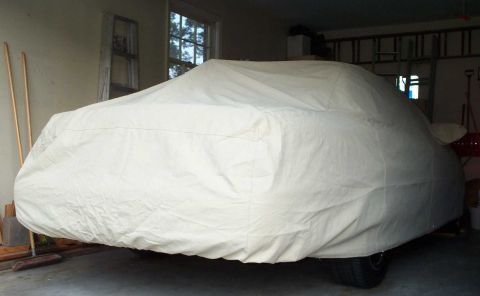 1998 Ford Crown Victoria - A vehicle is completely covered by a tan car cover, obscuring its make and model.