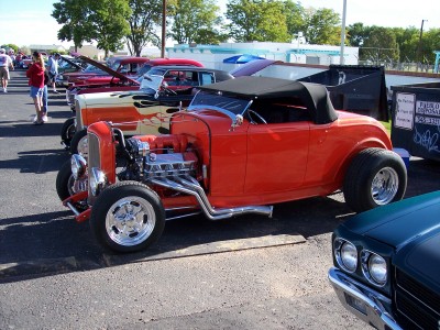 1972 Ford Ranchero - Orange hot rod convertible with exposed engine and black top, parked next to other cars.