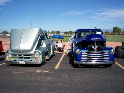 1972 Ford Ranchero - Two classic pickup trucks, a silver Ford and a blue Chevrolet, are parked in a lot with their hoods open.