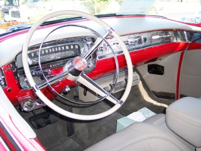 1972 Ford Ranchero - Interior view of a classic car, a prominent white steering wheel and a vibrant red dashboard with chrome accents.