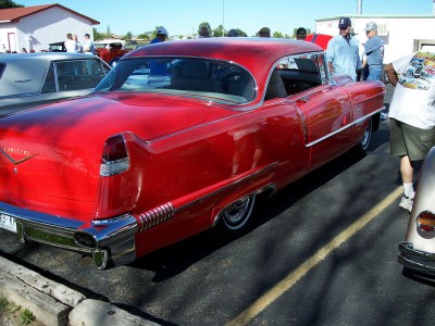 1972 Ford Ranchero - A bright red classic car is parked at an outdoor event with other vehicles and people nearby.