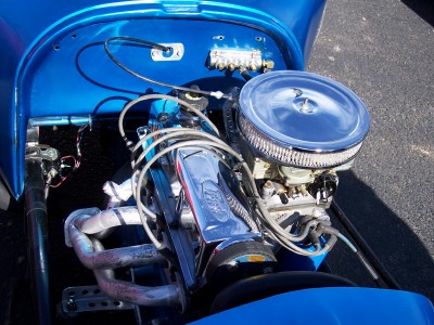 1972 Ford Ranchero - The engine bay of a custom car features a V8 engine with chrome accents and an open-element air filter.