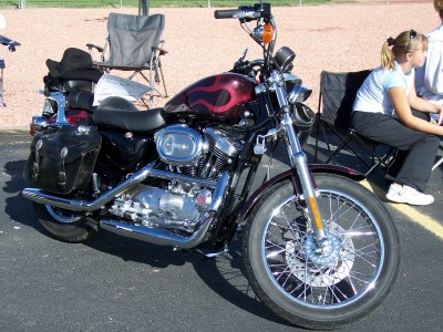 1972 Ford Ranchero - A motorcycle is parked outdoors with people sitting in chairs nearby.