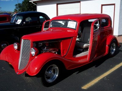 1972 Ford Ranchero - A red hot rod coupe with its doors and hood open, revealing the engine, parked next to a black car.