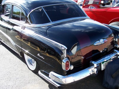 1972 Ford Ranchero - Rear view of a black 1952 Buick Special sedan, chrome accents and whitewall tires, parked next to a red vehicle.