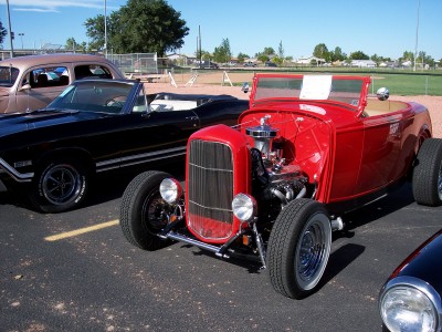 1972 Ford Ranchero - A red 1932 Ford hot rod convertible is parked alongside other vehicles on a sunny day.