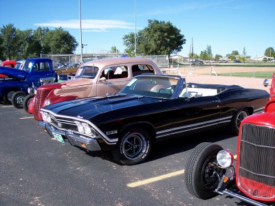 1972 Ford Ranchero - A black convertible is parked among other vintage vehicles under a clear blue sky.