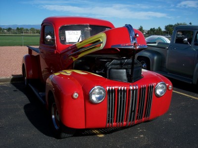 1972 Ford Ranchero - A bright red 1941 Ford pickup truck is displayed with its hood open, revealing the engine compartment and custom flame paint on the fender.