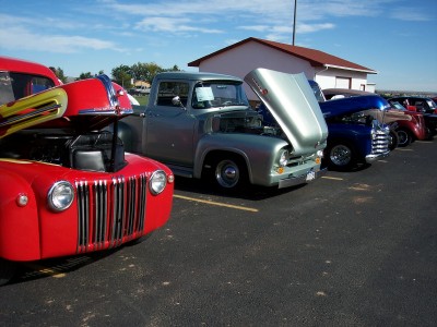1972 Ford Ranchero - A row of classic trucks, including a silver 1956 Ford F-100, are displayed with their hoods open.