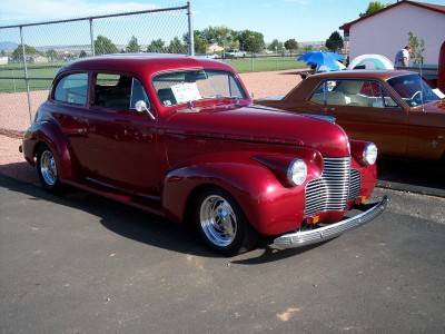 1972 Ford Ranchero - A red 1940s sedan hot rod is parked next to a brown coupe on a sunny day.