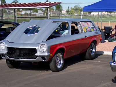 1972 Ford Ranchero - A custom two-tone station wagon is parked with its hood up, displaying a prominent scoop and numerous stickers on the rear window.
