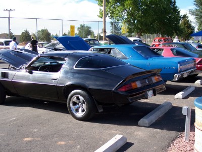 1972 Ford Ranchero - A black 1977 Chevrolet Camaro is parked with its hood open, alongside other vehicles at an outdoor event.