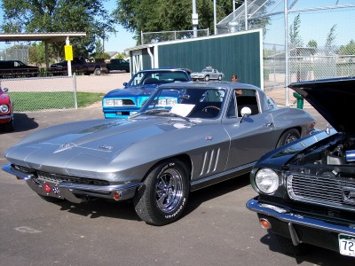 1972 Ford Ranchero - A silver 1965 Chevrolet Corvette Sting Ray coupe is parked next to other vehicles.