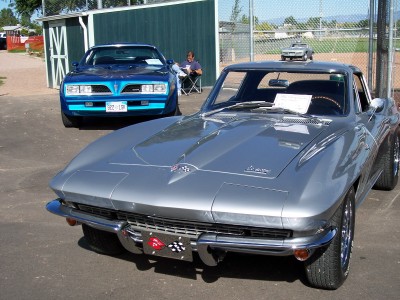 1972 Ford Ranchero - Silver 1965 Corvette Sting Ray parked next to a blue Pontiac Firebird at an outdoor event.