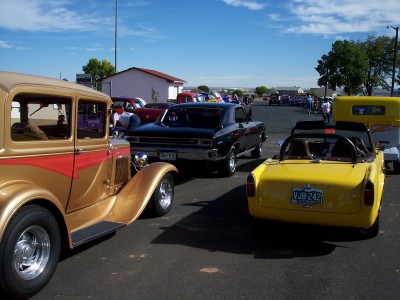 1972 Ford Ranchero - Multiple vehicles, including a hot rod and a yellow car, are parked together under a clear sky.