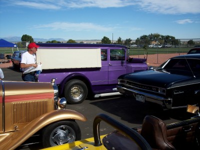 1972 Ford Ranchero - A purple pickup truck with a white sign is parked next to other vehicles.