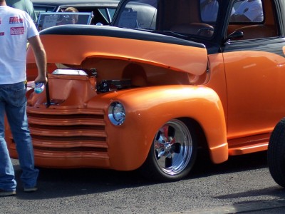 1972 Ford Ranchero - A custom orange and black truck is on display with its hood open, revealing the engine bay.