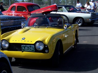 1972 Ford Ranchero - A yellow Triumph convertible is parked at an outdoor car show with other classic vehicles.