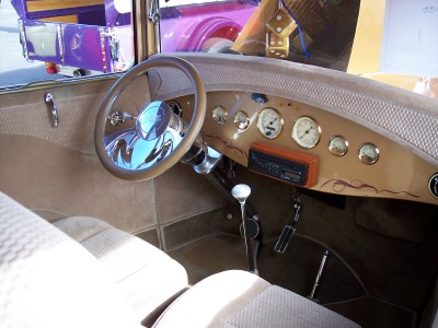 1972 Ford Ranchero - The interior of a vintage car shows a tan dashboard with several gauges and a wooden steering wheel.