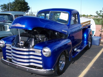 1972 Ford Ranchero - A blue pickup truck with custom flames and an open hood is parked next to another vehicle.