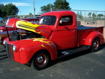 1972 Ford Ranchero - A red pickup truck with flame graphics on the hood and fenders is parked outdoors with its hood open.