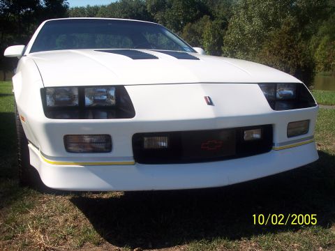 1988 Chevrolet Camaro - Front view of a white 1988 Chevrolet Camaro, distinctive black hood vents and the iconic Chevrolet bowtie emblem.