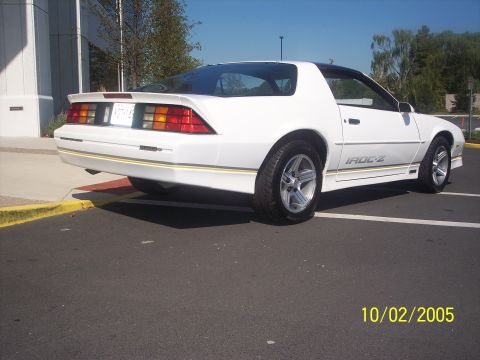 1988 Chevrolet Camaro - A white 1988 Chevrolet Camaro IROC-Z is shown from the rear quarter angle in a parking lot.