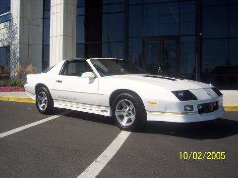 1988 Chevrolet Camaro - A white 1988 Chevrolet Camaro IROC-Z is shown parked outside a building.