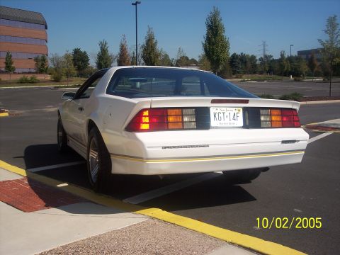 1988 Chevrolet Camaro - Rear view of a white 1988 Chevrolet Camaro, distinctive taillights and gold pinstriping along the lower body.