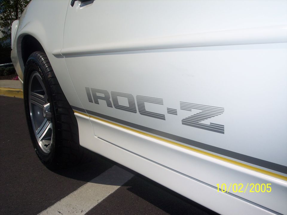 Side view of a white car with an IROC-Z decal and a yellow stripe