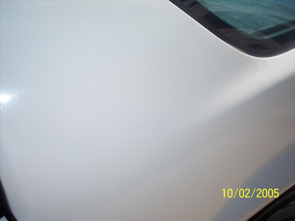 White car hood with reflection and a corner of the windshield. Watermark says 10/02/2005 SUPERMOTORS www.supermotors.net