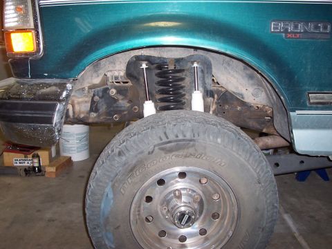 1996 Ford Bronco - Close-up of the front suspension and wheel well of a 1996 Ford Bronco XLT, showing new shocks and springs.