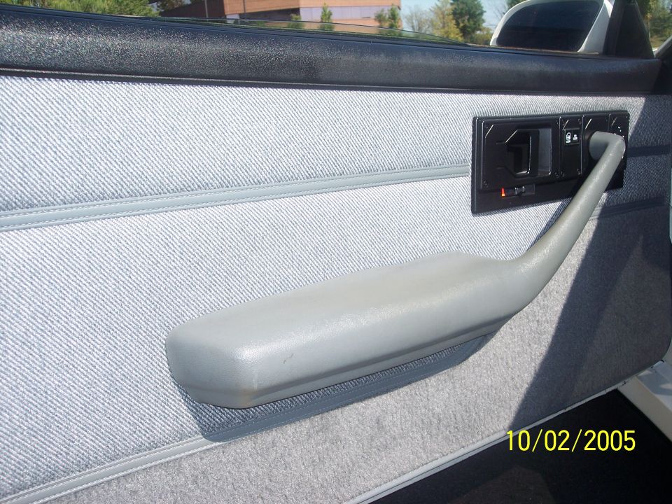 Gray cloth door panel with armrest and power window switches in a coupe