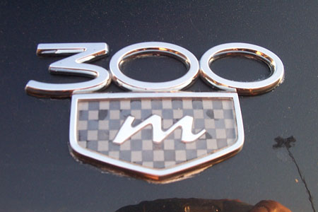 1999 Chrysler 300M - A chrome 300M badge is shown on a dark car exterior.
