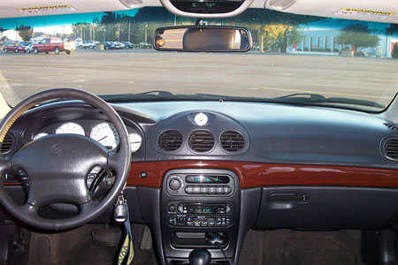 1999 Chrysler 300M - The interior of a 1999 Chrysler 300M shows a wood-trimmed dashboard with analog gauges and a central clock.