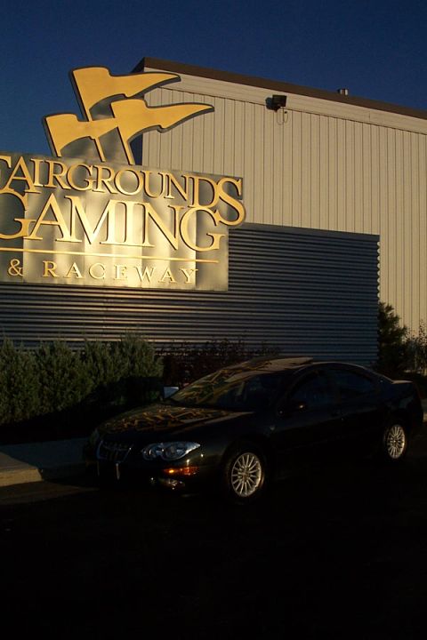 1999 Chrysler 300M - A black sedan is parked in front of the Fairgrounds Gaming & Raceway building during the day.