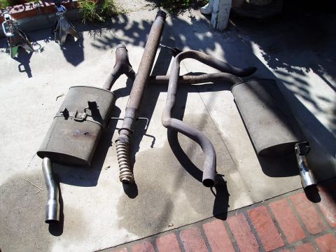 1993 Ford Taurus - Several used exhaust system components are arranged on a concrete surface, possibly for replacement or repair.