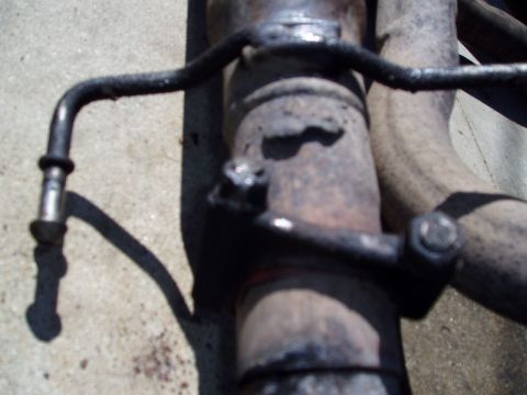1993 Ford Taurus - Close-up view of a vehicle's exhaust pipe and its supporting bracket.
