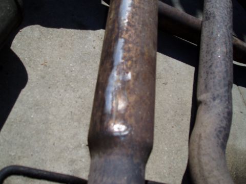 1993 Ford Taurus - Close-up of two old, rusty exhaust pipes on a concrete surface.