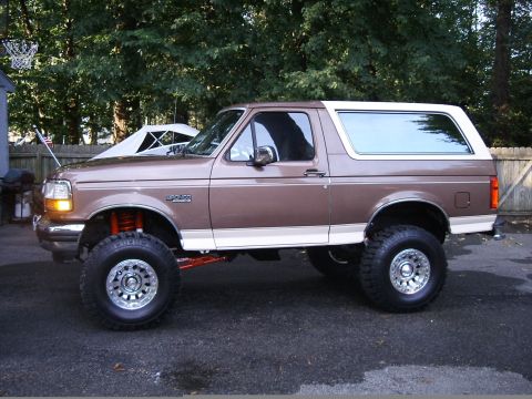 1993 Ford Bronco - A lifted Ford Bronco with custom wheels and tires sits in a driveway.